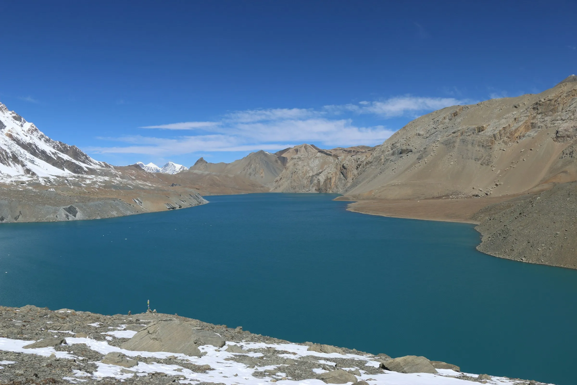 Turquoise Tilicho Lake ringed by bare slopes and snow peaks